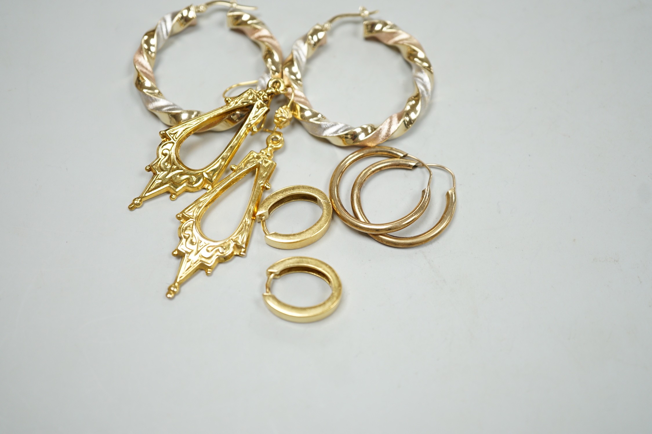 A modern pair of Italian three colour 14k hoop earrings, 35mm, 5.9 grams, a small pair of 750 oval earrings, 5.4 grams, a pair of 9ct gold Victorian style drop earrings, 2.7 grams and a pair of yellow metal hoop earrings